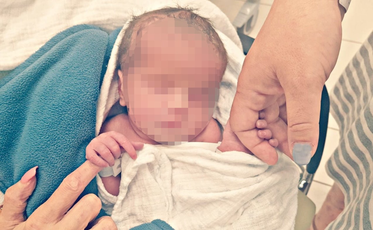 ידיהן של אשרת והאם הפונדקאית, סימה עמר יחד עם התינוקת