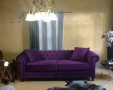 מבט אל הסלון עם פריט דומיננטי בצורת ספה סגולה יפיפיה